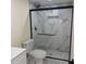 A shower featuring glass doors, marble-look tile and a shower head with rainfall feature is displayed at 3301 Clydesdale Dr, Holiday, FL 34691