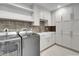 Well-equipped laundry room with stainless steel washer and dryer and farm sink at 455 Pinellas Bayway S # 2A, Tierra Verde, FL 33715