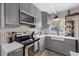 This is a well-lit kitchen with gray cabinets, white countertops, and stainless steel appliances at 5805 S Hubert Ave, Tampa, FL 33616