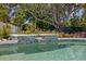 Inviting pool with tile accents and a tranquil waterfall feature, set against a backdrop of lush greenery and mature trees at 5805 S Hubert Ave, Tampa, FL 33616