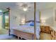 Bedroom with four-poster bed, side tables with lamps, and a mirrored closet showcasing an attached bathroom at 612 Fairmont Ave # D, Safety Harbor, FL 34695