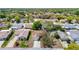 A sunny aerial view shows the single-Gathering home nestled in a lush neighborhood with mature trees and well-maintained lawns at 10819 Los Santos Dr, Port Richey, FL 34668