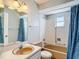 Well-maintained bathroom featuring a blue shower curtain, tiled walls and peach colored sink at 10819 Los Santos Dr, Port Richey, FL 34668