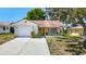 Charming single-story home features a cheerful yellow door, attached garage, and well-maintained lawn at 10819 Los Santos Dr, Port Richey, FL 34668