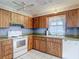 Well-lit kitchen features wood cabinetry, white appliances, and a window over the sink at 10819 Los Santos Dr, Port Richey, FL 34668