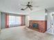 Spacious living room with a brick fireplace, ceiling fan, and large window with sheer curtains at 10819 Los Santos Dr, Port Richey, FL 34668