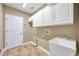 Large laundry room with tile floors, utility sink, and white cabinets for plenty of storage at 15714 Ibisridge Dr, Lithia, FL 33547