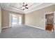 Large main bedroom with tray ceiling, fan, and sliding glass doors leading to outdoor living space at 15714 Ibisridge Dr, Lithia, FL 33547