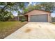 Charming single-story home featuring a gray garage door and a spacious concrete driveway at 16039 Frost Dr, Hudson, FL 34667