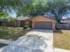 Single-story home with a two-car garage and a well-manicured front lawn and mature trees at 16039 Frost Dr, Hudson, FL 34667