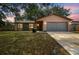 Charming single-story home featuring a gray garage door and a well-maintained lawn at 16039 Frost Dr, Hudson, FL 34667