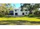 Backyard featuring a pool, large grassy area, screened in lanai, and mature trees at 1800 Salem Ct, Dunedin, FL 34698