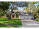 Charming two-story home with a three-car garage, mature trees, and manicured lawn at 1800 Salem Ct, Dunedin, FL 34698