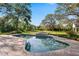 Inviting pool area with a hot tub, brick patio, and lush greenery in the spacious backyard at 1800 Salem Ct, Dunedin, FL 34698