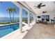 A covered patio featuring ceiling fans, stone floors, and a pool with water views at 1901 Carolina Ne Ave, St Petersburg, FL 33703
