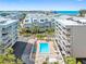 Aerial view of a condo complex with a pool, hot tub, and lush landscaping near the ocean at 19925 Gulf Blvd # 402, Indian Shores, FL 33785