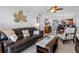 Spacious living room with tile floors, leather sofa, chair, and decorative leaf wall decor at 19925 Gulf Blvd # 402, Indian Shores, FL 33785