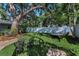 Serene backyard featuring lush artificial grass, a hammock, mature trees, and a charming bistro set at 202 S Hesperides St, Tampa, FL 33609
