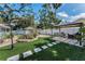 Expansive backyard with artificial turf, brick patio, lounge seating, outdoor kitchen, and lush greenery at 202 S Hesperides St, Tampa, FL 33609