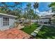 Beautiful backyard with artificial turf, brick patio, outdoor kitchen, lounge seating, and mature landscaping at 202 S Hesperides St, Tampa, FL 33609