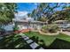 Landscaped backyard featuring artificial turf, brick patio, stepping stones, and mature trees, offering a peaceful retreat at 202 S Hesperides St, Tampa, FL 33609