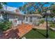 Charming home featuring a brick patio, manicured lawn, mature trees, and cozy outdoor lighting at 202 S Hesperides St, Tampa, FL 33609