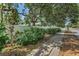 Sidewalk view of home's white fence, lush landscaping and mature trees at 202 S Hesperides St, Tampa, FL 33609