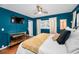 A primary bedroom featuring blue accent walls, ceiling fan, windows, mirrored dresser, and king size bed at 202 S Hesperides St, Tampa, FL 33609