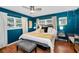 A primary bedroom with blue accent walls, ceiling fan, windows, and a king size bed with a gray bench at 202 S Hesperides St, Tampa, FL 33609