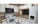 Well-equipped kitchen with granite counters, white cabinets, black microwave, and electric range at 2213 Fluorshire Dr, Brandon, FL 33511