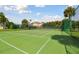 Beautifully maintained community tennis court surrounded by a secure fence with tropical trees and landscaping at 2700 Bayshore Blvd # 522, Dunedin, FL 34698