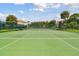 Outdoor tennis court with a green surface, white lines, surrounded by a chain-link fence and tropical trees at 2700 Bayshore Blvd # 522, Dunedin, FL 34698