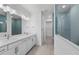 Modern bathroom with double vanity, quartz countertops, stylish mirrors, and a glass-enclosed shower with tiled walls at 29156 Coral Harbour Dr, Englewood, FL 34223