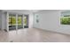 Open living room with sliding doors to screened patio, neutral tile flooring, and natural light from multiple windows at 29156 Coral Harbour Dr, Englewood, FL 34223