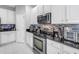 Modern kitchen with white cabinets, stainless steel appliances, black countertops, and a stylish tile backsplash at 3009 Banyan Hill Ln, Land O Lakes, FL 34639