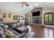 Cozy living room features stone fireplace, large windows, leather furniture, ceiling fan and wood floors at 30723 Reed Rd, Dade City, FL 33523