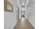 Long hallway with tiled floors, leading towards a modern glass-accented front door, and a stairway at 3096 Great Banyan Way, Wesley Chapel, FL 33543