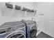Modern laundry room featuring front-load washer and dryer, storage shelves, and a sink at 3096 Great Banyan Way, Wesley Chapel, FL 33543