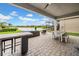 Covered patio with stylish outdoor furniture and views of a serene lake and manicured lawn at 3096 Great Banyan Way, Wesley Chapel, FL 33543