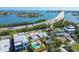 Stunning aerial view of waterfront homes with a pool and covered patio, located near a bridge and beautiful bay at 3210 E Maritana Dr, St Pete Beach, FL 33706