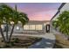 Charming home exterior with tropical landscaping, walkway, and neutral paint at twilight at 3210 E Maritana Dr, St Pete Beach, FL 33706