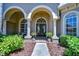 Elegant home entrance with arched doorway, decorative plants, and manicured landscaping at 3212 Sunset Lakes Blvd, Land O Lakes, FL 34638