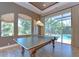 Spacious game room featuring a ping pong table and sliding doors to the screened pool area at 3212 Sunset Lakes Blvd, Land O Lakes, FL 34638