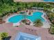 Aerial view showcasing a uniquely shaped community pool surrounded by lounge chairs and palm trees at 32721 Brooks Hawk Ln, Wesley Chapel, FL 33543