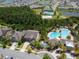 Aerial view of homes near a community pool, tennis courts, and wooded area with small lake at 32721 Brooks Hawk Ln, Wesley Chapel, FL 33543
