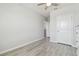 Neutrally painted bedroom with gray wood-look floors, a ceiling fan and an adjacent open door at 32721 Brooks Hawk Ln, Wesley Chapel, FL 33543