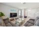 Open living room with gray sofa, large TV, and bright natural light at 32721 Brooks Hawk Ln, Wesley Chapel, FL 33543