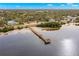 Aerial view of pier near residences extending into the water, surrounded by trees and a sandy beach at 407 Indiana Ave, Crystal Beach, FL 34681