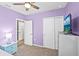 Bedroom with purple walls and featuring a ceiling fan, TV on bureau, closet, and panel doors at 44239 Frontier Dr, Punta Gorda, FL 33982