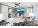 Cozy living room features a ceiling fan, TV, gray walls and sliding doors to the outdoor grill at 44239 Frontier Dr, Punta Gorda, FL 33982